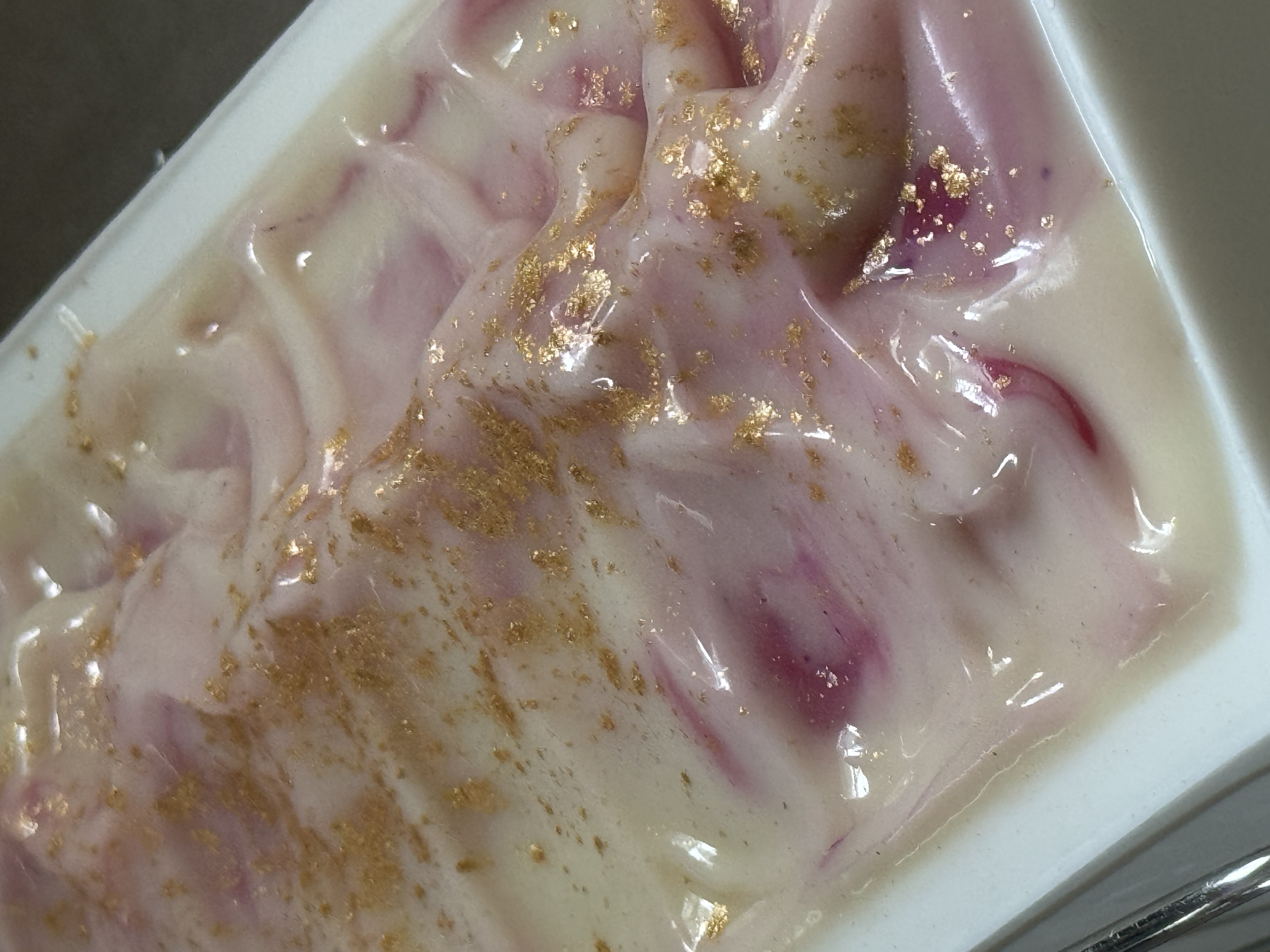 Rows of freshly cut cold process soap bars standing upright on parchment paper to cure — honeycomb oat bars, blue swirl bars, and lavender bars filling the frame.
